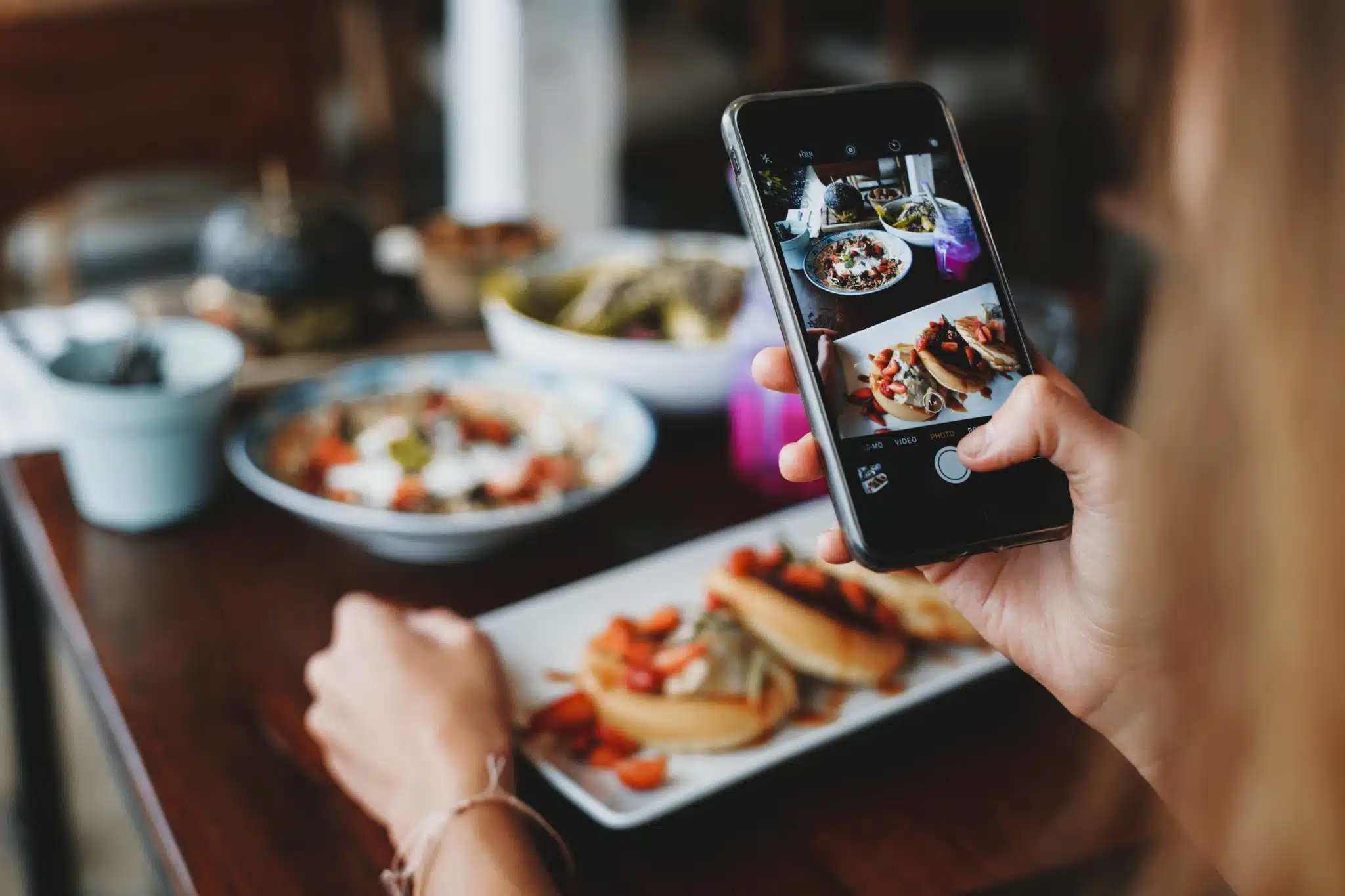 Crop woman taking shot of food on mobile phone